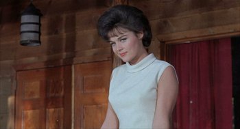 Movie still from “Kid Galahad” (1962), directed by Phil Karlson – A woman in a white dress standing next to a wooden wall; Close Up shot, Low angle