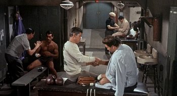 Movie still from “Kid Galahad” (1962), directed by Phil Karlson – A man is shaking hands with another man in a room; Wide shot, High angle