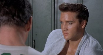 Movie still from “Kid Galahad” (1962), directed by Phil Karlson – A man in a white towel looking at himself in the mirror; Close Up shot, Over the shoulder angle