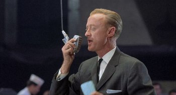 Movie still from “Kid Galahad” (1962), directed by Phil Karlson – A man in a suit and tie holding a cell phone to his ear; Close Up shot, Low angle