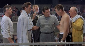 Movie still from “Kid Galahad” (1962), directed by Phil Karlson – A group of men standing in a boxing ring; Medium shot, Low angle