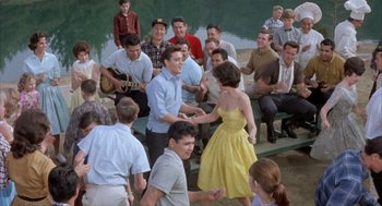 Movie still from “Kid Galahad” (1962), directed by Phil Karlson – A group of people gathered around each other in a park; Wide shot, High angle