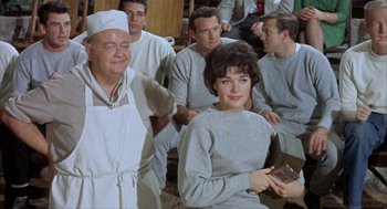 Movie still from “Kid Galahad” (1962), directed by Phil Karlson – A group of men and a woman sitting next to each other; Medium shot, Over the shoulder angle