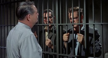 Movie still from “Kid Galahad” (1962), directed by Phil Karlson – A group of men standing next to each other in front of a jail cell; Medium shot, Over the shoulder angle