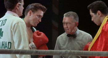 Movie still from “Kid Galahad” (1962), directed by Phil Karlson – A man in a boxing ring talking to another man in a boxing ring; Medium shot, Low angle