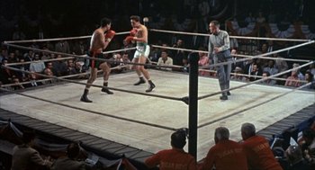 Movie still from “Kid Galahad” (1962), directed by Phil Karlson – Two men are boxing in a boxing ring while a crowd watches; Wide shot, High angle