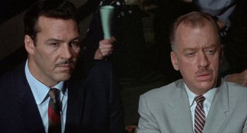 Movie still from “Kid Galahad” (1962), directed by Phil Karlson – Two men in suits sitting next to each other in a room; Close Up shot, Over the shoulder angle