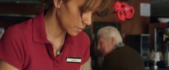 Movie still from “Kidnap” (2017), directed by Luis Prieto – A woman wearing a name tag in front of an older man; Close Up shot, High angle