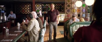Movie still from “Kidnap” (2017), directed by Luis Prieto – A man standing in front of a group of people in a restaurant; Medium shot, Over the shoulder angle