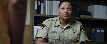 Movie still from “Kidnap” (2017), directed by Luis Prieto – A female police officer is sitting in front of a book shelf; Close Up shot, Over the shoulder angle