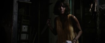 Movie still from “Kidnap” (2017), directed by Luis Prieto – A woman holding a knife in a dark room; Medium shot, Over the shoulder angle