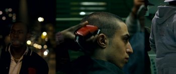 Movie still from “Kidulthood” (2006), directed by Menhaj Huda – A man getting his hair cut by a barber; Close Up shot, Over the shoulder angle