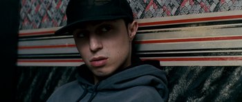 Movie still from “Kidulthood” (2006), directed by Menhaj Huda – A young man wearing a hat and a sweatshirt; Close Up shot, High angle