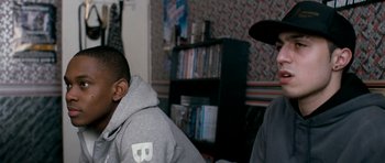 Movie still from “Kidulthood” (2006), directed by Menhaj Huda – Two young men sitting in front of a book shelf; Close Up shot, Over the shoulder angle