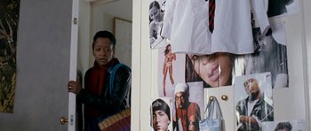 Movie still from “Kidulthood” (2006), directed by Menhaj Huda – A man standing in front of a wall with pictures of people; Medium shot, Over the shoulder angle