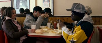 Movie still from “Kidulthood” (2006), directed by Menhaj Huda – A group of men sitting at a table eating food; Medium shot, Over the shoulder angle