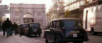 Movie still from “Kidulthood” (2006), directed by Menhaj Huda – A couple of black taxis driving down a street; Wide shot, Low angle