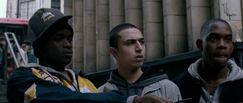 Movie still from “Kidulthood” (2006), directed by Menhaj Huda – Two young men standing next to each other on a street; Medium shot, Over the shoulder angle