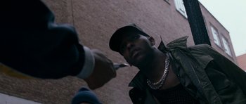 Movie still from “Kidulthood” (2006), directed by Menhaj Huda – A person taking a picture with a camera; Close Up shot, Low angle