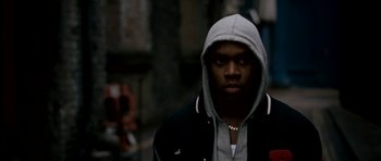 Movie still from “Kidulthood” (2006), directed by Menhaj Huda – A man in a hooded jacket standing on a street; Close Up shot, Low angle