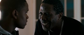 Movie still from “Kidulthood” (2006), directed by Menhaj Huda – A man with dreadlocks is laughing with another man; Close Up shot, Over the shoulder angle