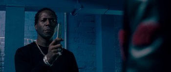 Movie still from “Kidulthood” (2006), directed by Menhaj Huda – A man standing in front of a brick wall holding a cell phone; Close Up shot, Low angle