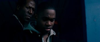 Movie still from “Kidulthood” (2006), directed by Menhaj Huda – A man in a black jacket is looking at the camera; Close Up shot, Over the shoulder angle