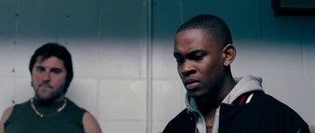 Movie still from “Kidulthood” (2006), directed by Menhaj Huda – A man standing next to a woman in a room; Close Up shot, Over the shoulder angle