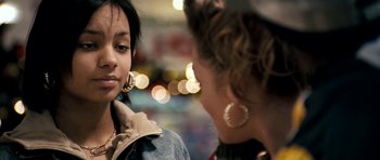 Movie still from “Kidulthood” (2006), directed by Menhaj Huda – Two women are standing in a room with lights in the background; Close Up shot, Over the shoulder angle