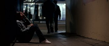 Movie still from “Kidulthood” (2006), directed by Menhaj Huda – A person sitting on the ground in the dark; Medium shot, Low angle