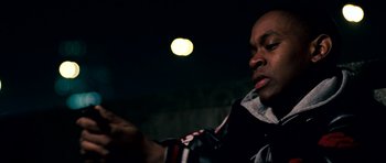 Movie still from “Kidulthood” (2006), directed by Menhaj Huda – A man holding a beer in his hand while standing in front of a wall; Close Up shot, Low angle