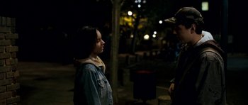 Movie still from “Kidulthood” (2006), directed by Menhaj Huda – A young girl standing next to a tree at night; Medium shot, Over the shoulder angle