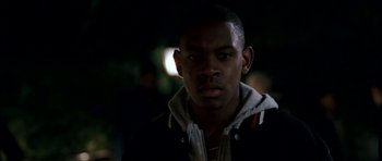 Movie still from “Kidulthood” (2006), directed by Menhaj Huda – A man in a black jacket is looking at the camera; Close Up shot, Over the shoulder angle