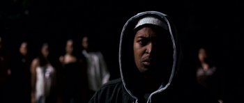 Movie still from “Kidulthood” (2006), directed by Menhaj Huda – A man in a hooded sweatshirt is in the dark; Close Up shot, Low angle