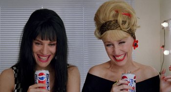 Movie still from “Kika” (1993), directed by Pedro Almodóvar – A couple of women sitting next to each other holding soda cans; Close Up shot, High angle