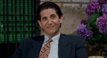 Movie still from “Kika” (1993), directed by Pedro Almodóvar – A person wearing a suit and tie; Close Up shot, Over the shoulder angle