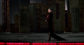 Movie still from “Kika” (1993), directed by Pedro Almodóvar – A woman in a long black dress walking on a stage; Wide shot, Low angle