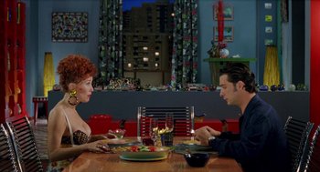 Movie still from “Kika” (1993), directed by Pedro Almodóvar – A woman and a man sitting at a dinner table; Medium shot, Over the shoulder angle