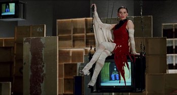 Movie still from “Kika” (1993), directed by Pedro Almodóvar – A woman in a red and white dress hanging on a television; Wide shot, Low angle