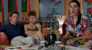 Movie still from “Kika” (1993), directed by Pedro Almodóvar – A group of women sitting on a couch in a room; Medium shot, Over the shoulder angle