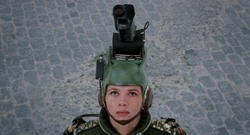 Movie still from “Kika” (1993), directed by Pedro Almodóvar – A woman wearing a helmet and holding a video camera on top of her head; Close Up shot, Overhead angle