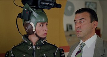 Movie still from “Kika” (1993), directed by Pedro Almodóvar – A man and a woman in military uniforms with a video camera on their head; Close Up shot, Over the shoulder angle