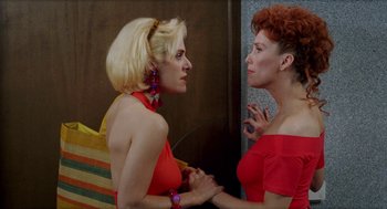 Movie still from “Kika” (1993), directed by Pedro Almodóvar – Two women are talking to each other in front of a wall; Medium shot, Over the shoulder angle