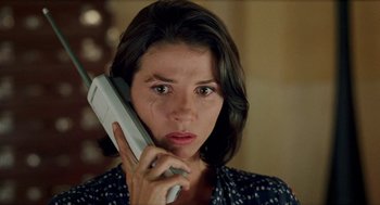 Movie still from “Kika” (1993), directed by Pedro Almodóvar – A woman holding a cell phone up to her ear; Close Up shot, Low angle