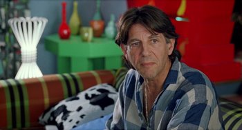 Movie still from “Kika” (1993), directed by Pedro Almodóvar – A person sitting on a couch; Close Up shot, Over the shoulder angle