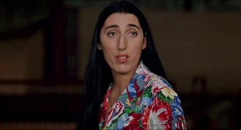 Movie still from “Kika” (1993), directed by Pedro Almodóvar – A woman with long black hair wearing a colorful shirt; Close Up shot, High angle