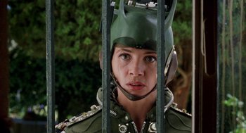 Movie still from “Kika” (1993), directed by Pedro Almodóvar – A woman wearing a green helmet and holding onto a metal cage; Close Up shot, Low angle