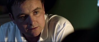Movie still from “Kill List” (2011), directed by Ben Wheatley – A person wearing a white shirt; Close Up shot, Over the shoulder angle