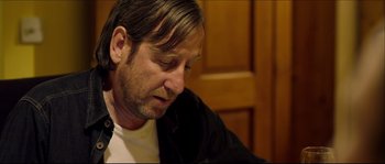 Movie still from “Kill List” (2011), directed by Ben Wheatley – A person sitting at a table; Close Up shot, Over the shoulder angle