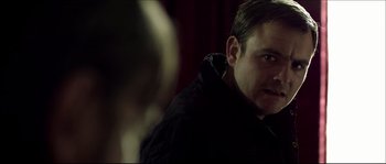 Movie still from “Kill List” (2011), directed by Ben Wheatley – A person wearing a black jacket; Close Up shot, Over the shoulder angle